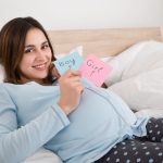 Pregnant Woman Holding Paper With Girl And Boy Written On It