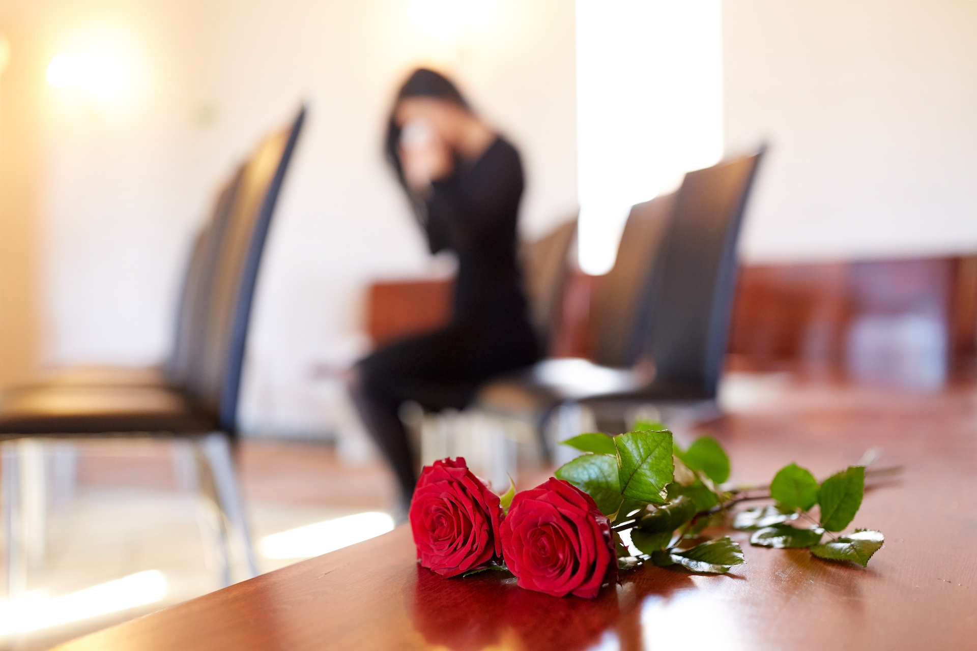 red roses and woman crying at funeral in church