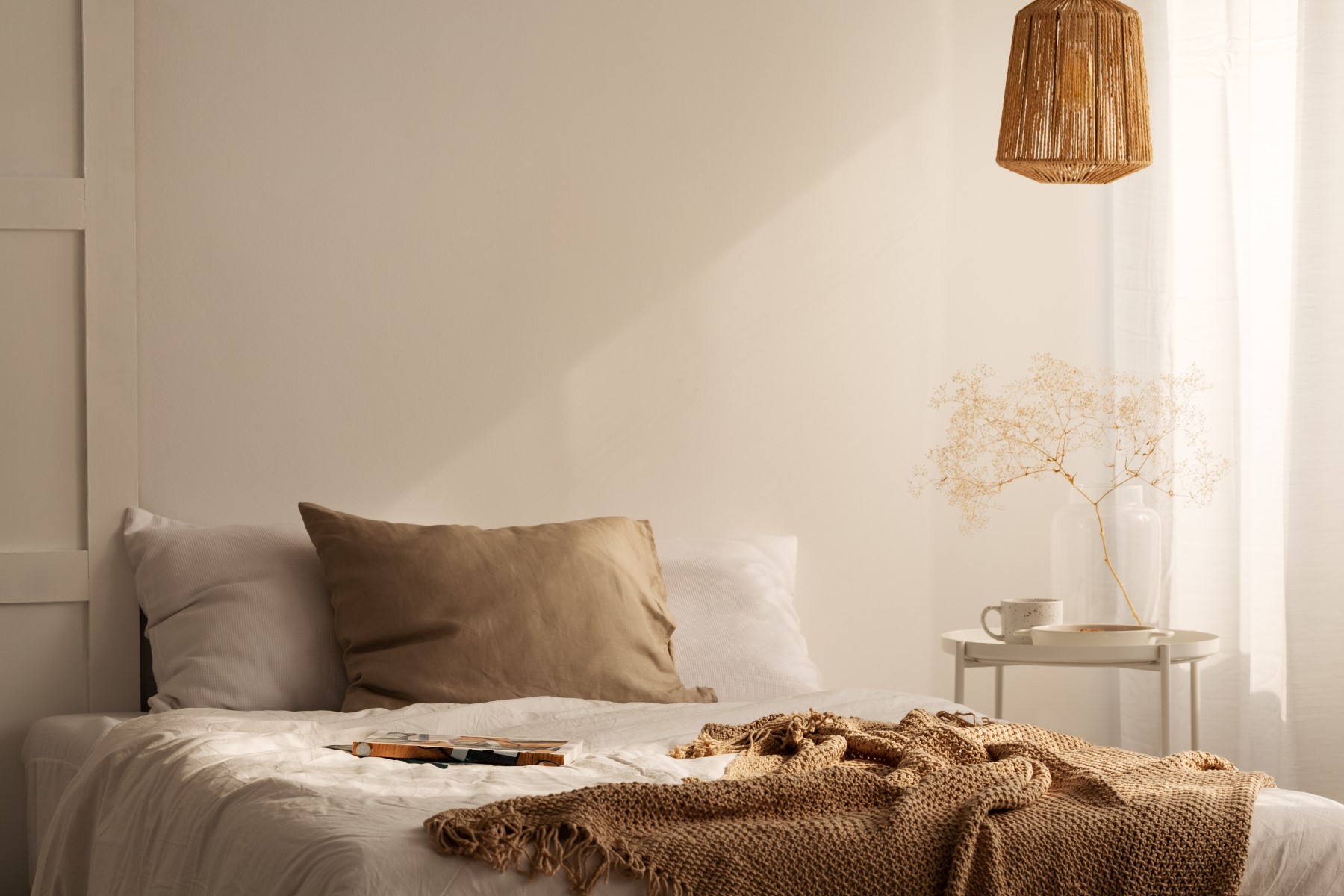 Closeup of bed with beige blanket and linen pillow in minimal be