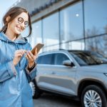 Woman with phone near the car outdoors