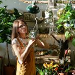 Young female gardener work with houseplants. Floral store business owner holding small flowerpot