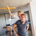 Yellow toy plane. Father and son is indoors at home together