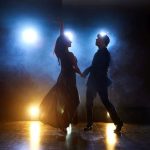 Skillful dancers performing in the dark room under the concert light and smoke. Sensual couple performing an artistic and emotional contemporary dance